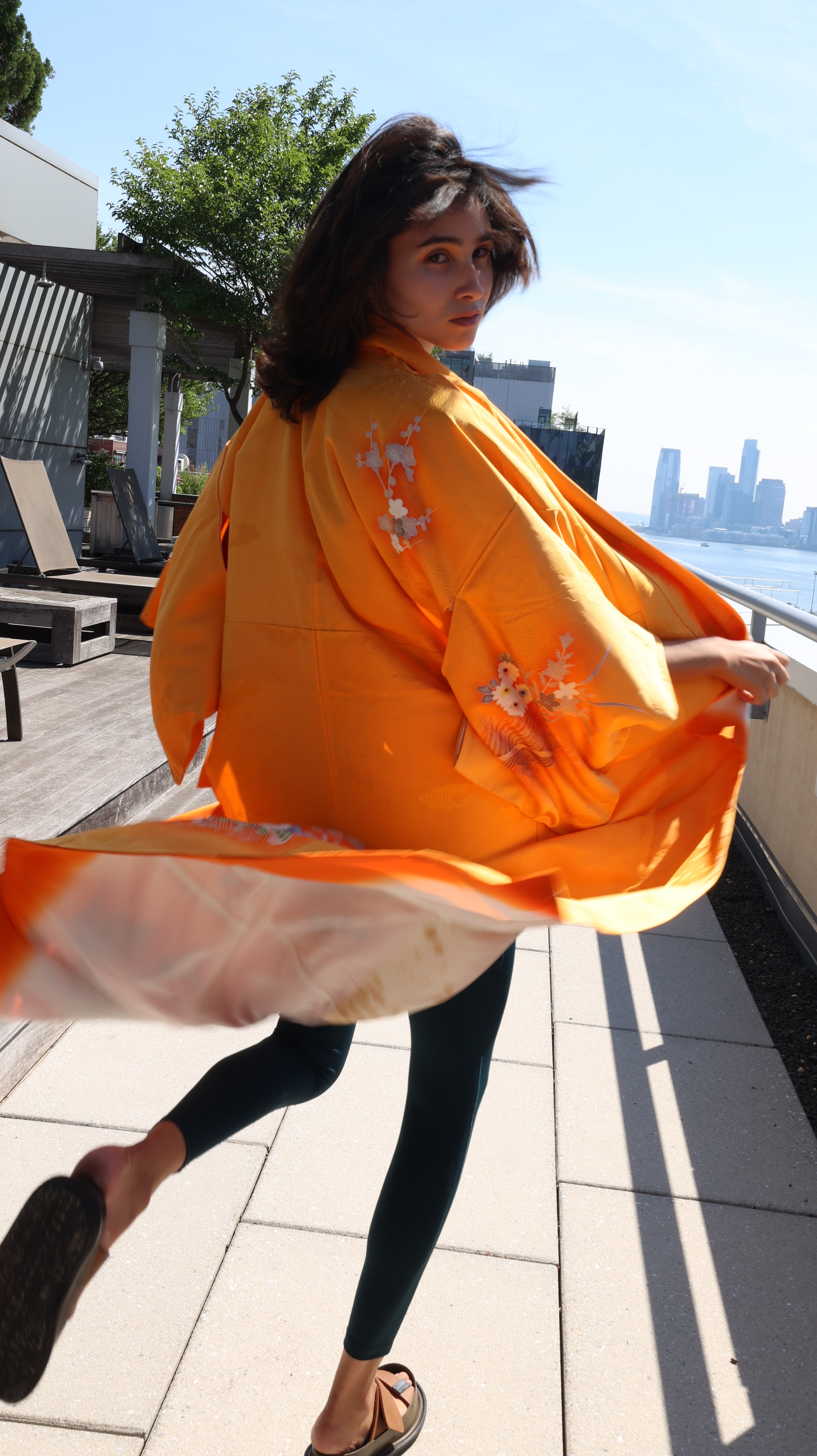 Woman in an orange kimono walking on a rooftop
